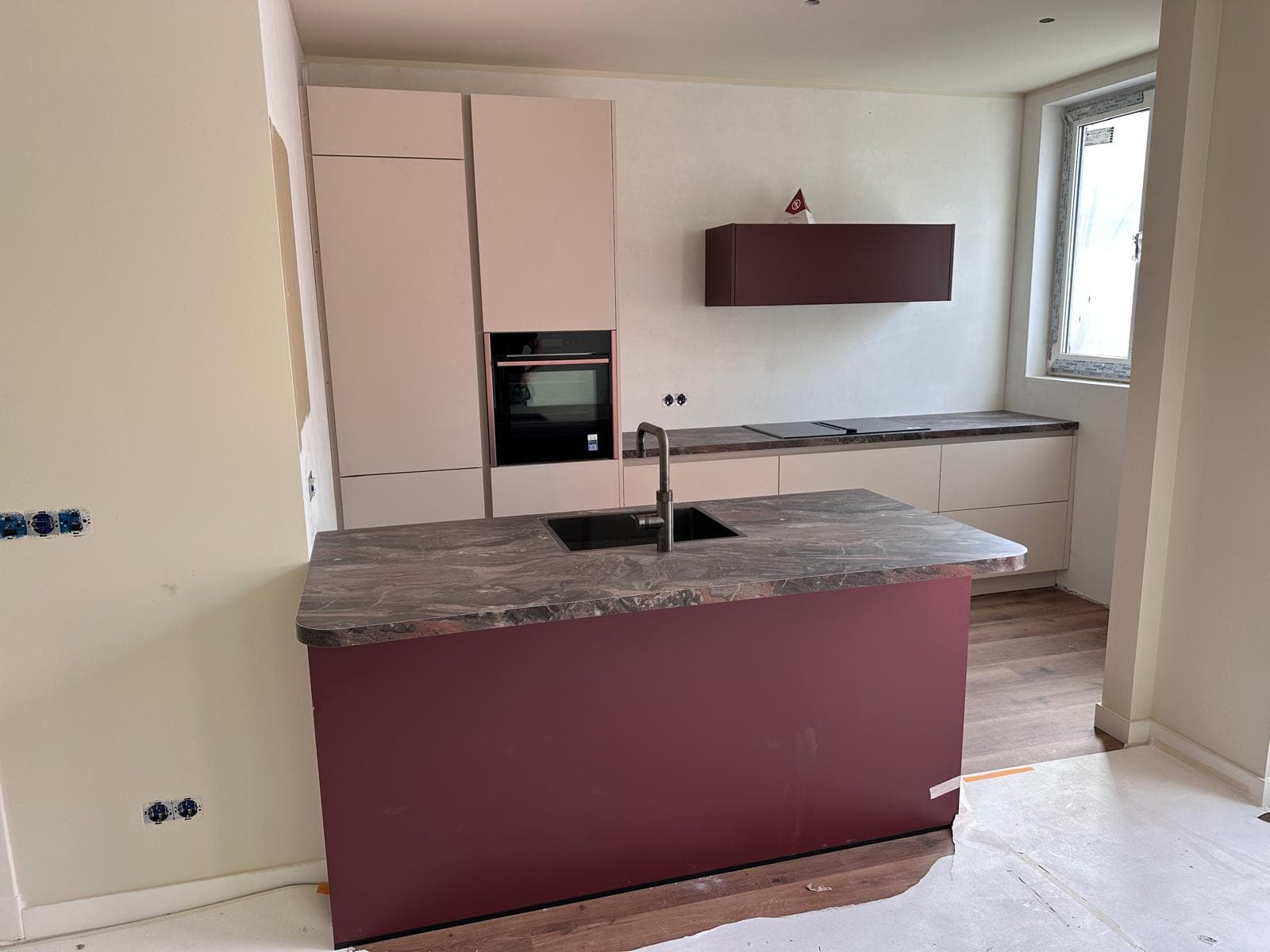 Keuken met bordeauxrood keukeneiland als middelpunt van de ruimte
