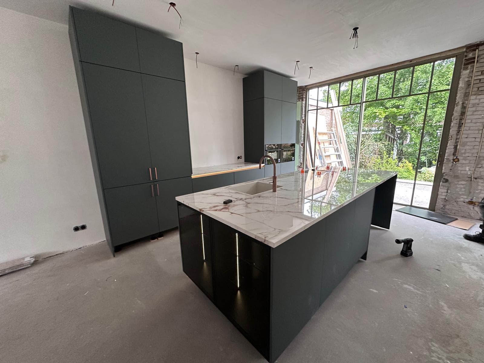 Donkere houtlook keuken met groot kookeiland, marmeren werkblad en koperen kraan